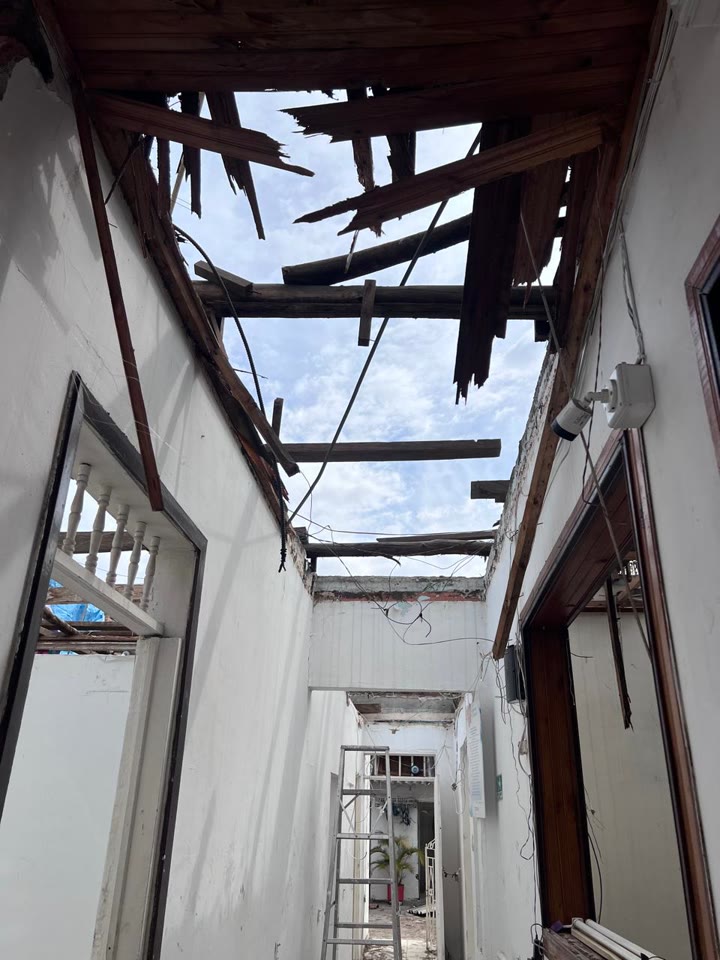 El corredor de la casa después del terremoto: el techo caído, las vigas de madera y el cielo abierto